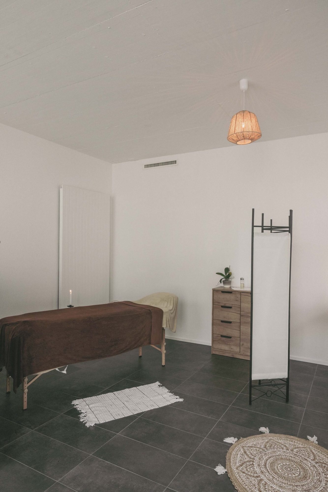 Table de massage du cabinet, drap brique et tapis rond