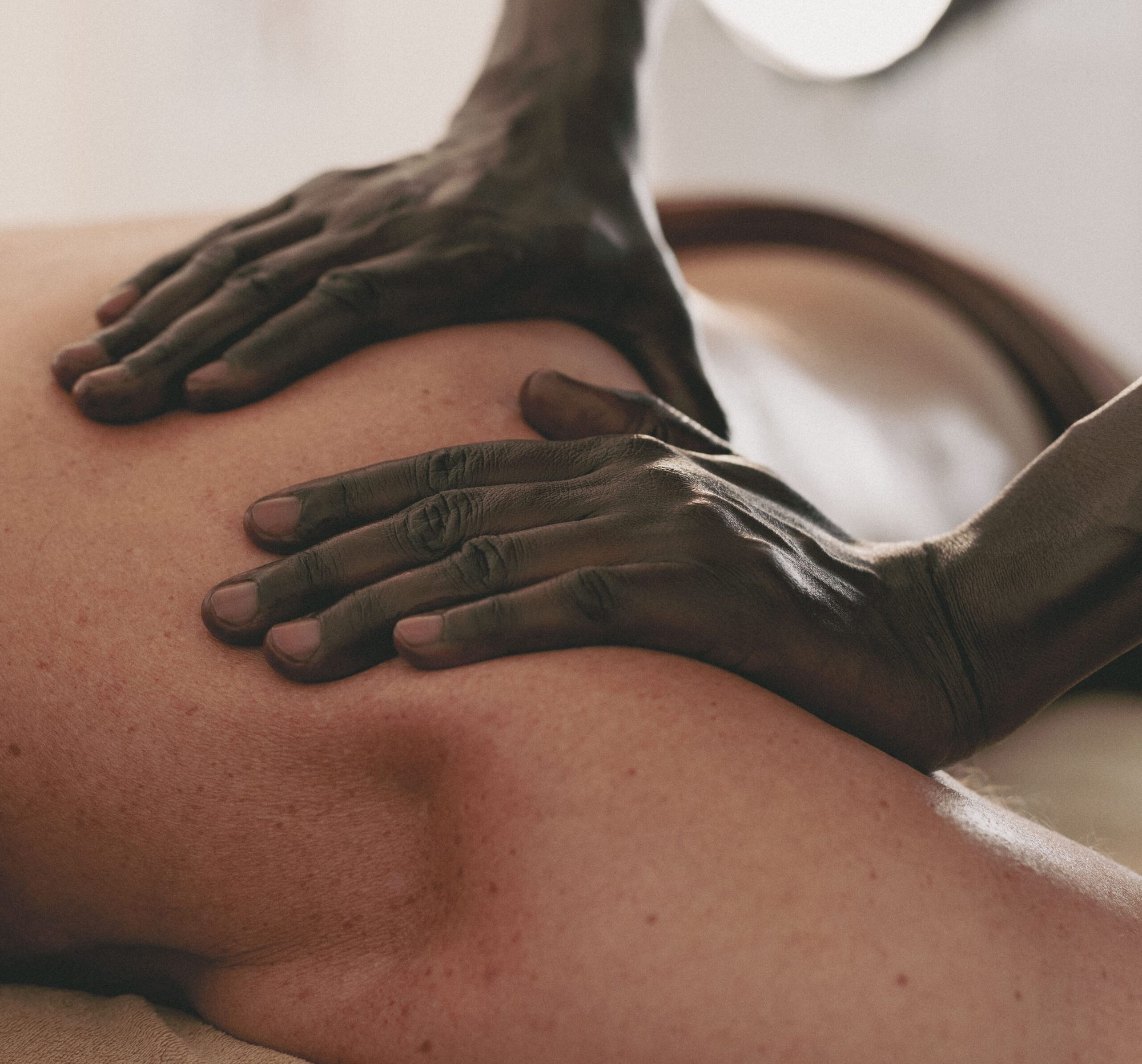 Mains qui massent l’épaule d’une personne allongée